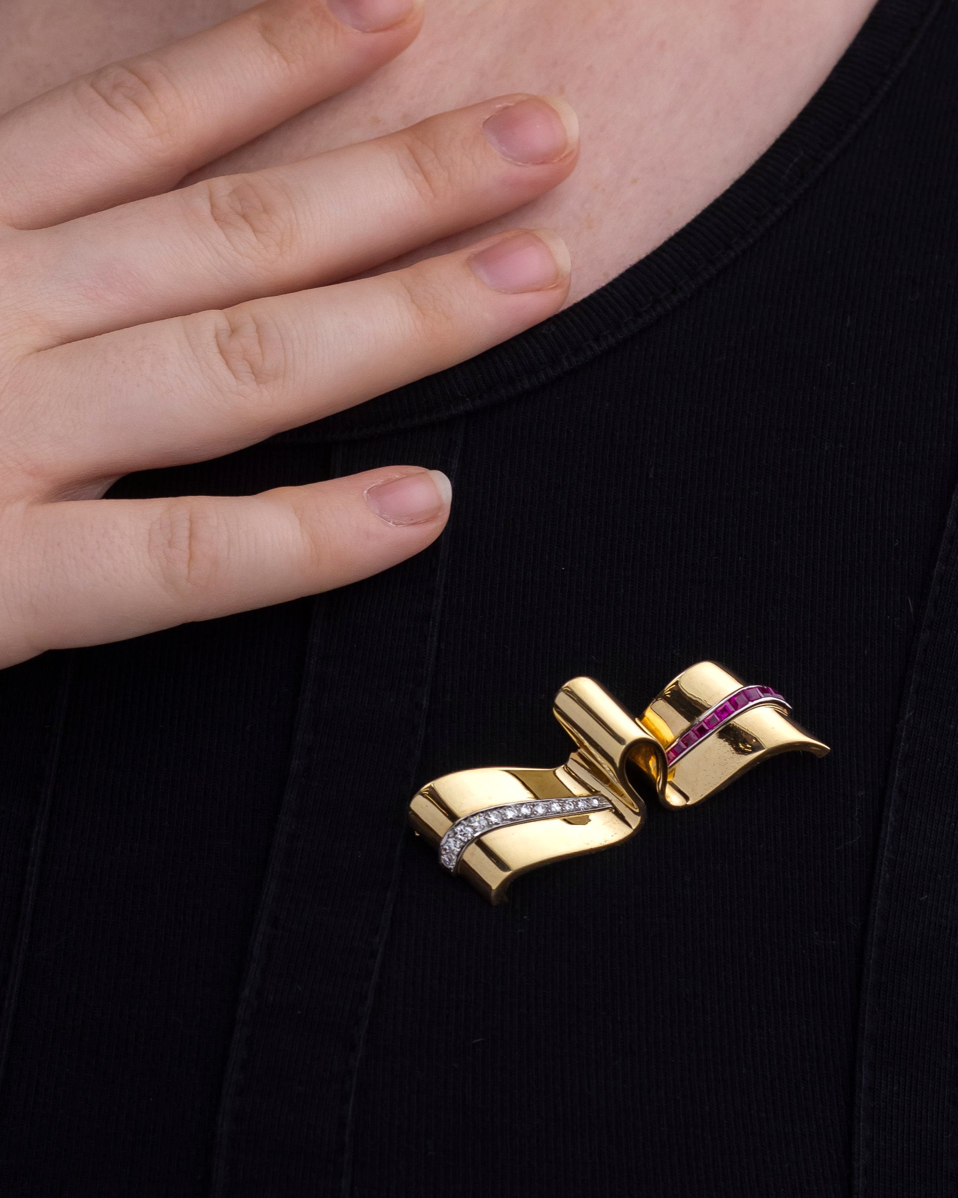 Gold bow-shaped brooch with purple center on a black background